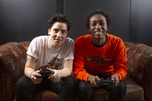 Two non binary friends playing video games laughing